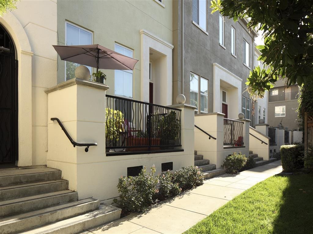 Apartments for Rent in San Jose, CA - Museum Park - Building Exterior Showcasing Cream Walls and Patios, with Walking Path and Lush Greenery