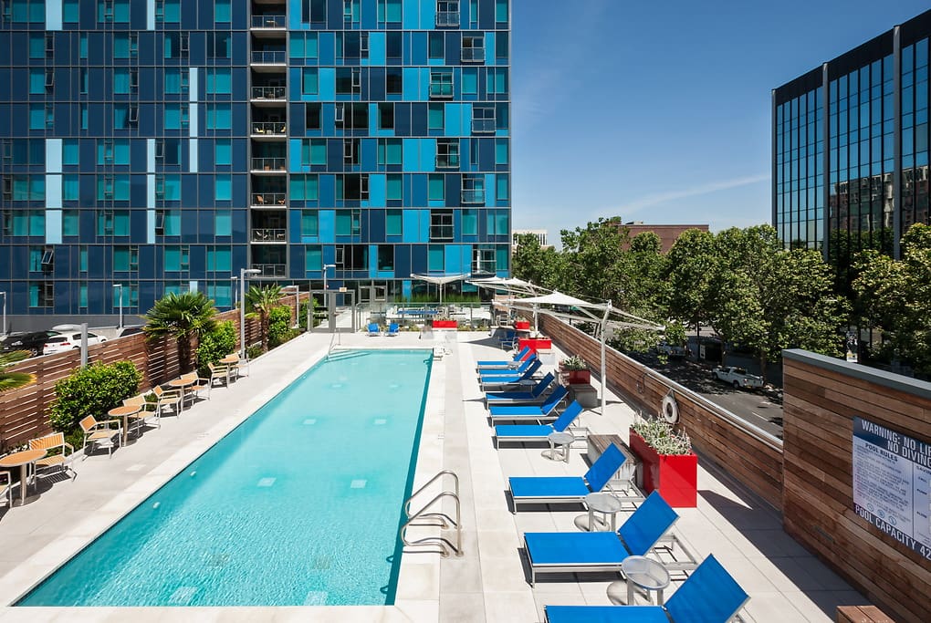 Luxury Apartments San Jose, CA - One South Market - Large Pool Area with Lounge Chairs, Table Seating and Lush Greenery