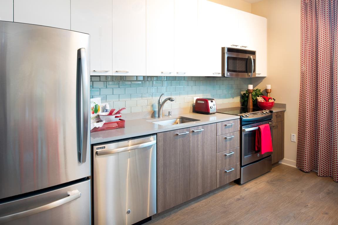 San Jose, CA Apartments for Rent - One South Market - Kitchen with Wood-Style Flooring, Modern Backsplash, and Full Stainless Steel Appliances Package